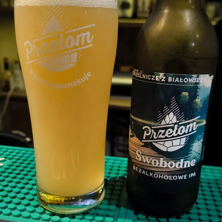 Szklanka pszenicznego piwa i butelka na barowej macie