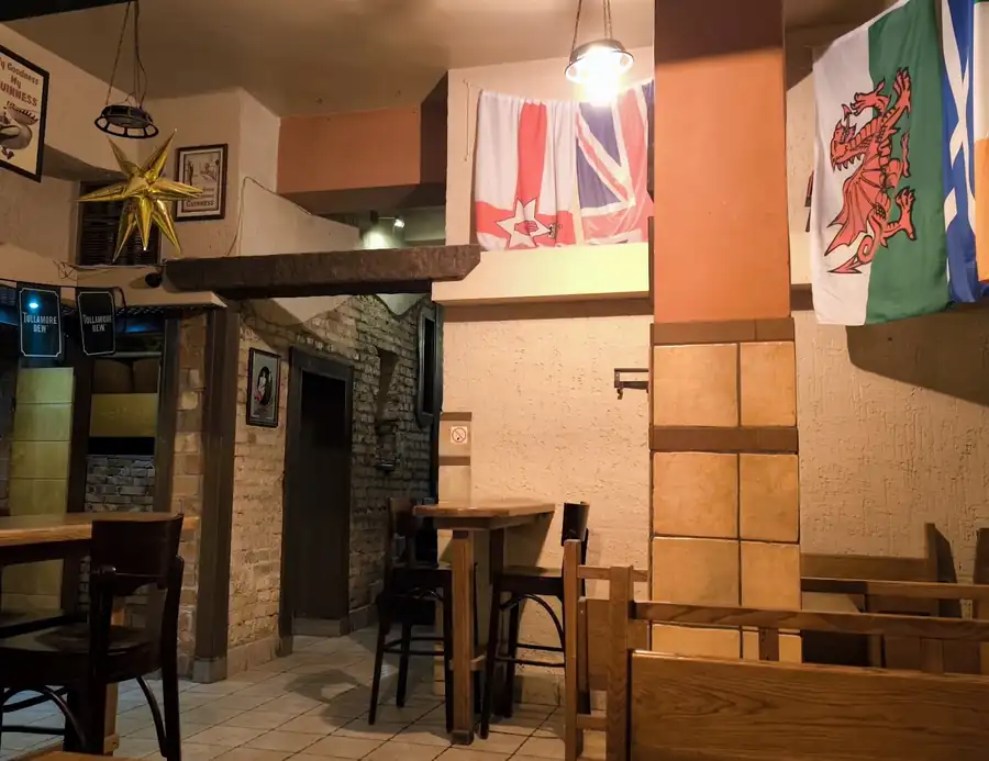 Sala z drewnianymi stolikami i flagami na ścianach