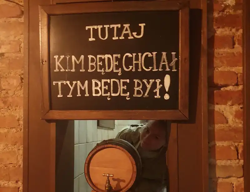 Kredowa tabliczka „Tutaj kim będę chciał, tym będę był!” i beczka w oknie